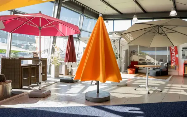 Moderne Ausstellung von Sonnenschirmen in verschiedenen Farben in einem hellen Showroom.