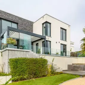 Modernes Einfamilienhaus mit großer Glasfassade, Garten und Terrasse in ruhiger Wohnlage.