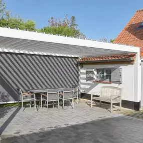 Moderne Terrasse mit Überdachung, Gartenmöbeln und Sichtschutz am Einfamilienhaus.