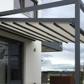 Moderne Terrassenüberdachung aus Aluminium mit Markise an einem Einfamilienhaus.